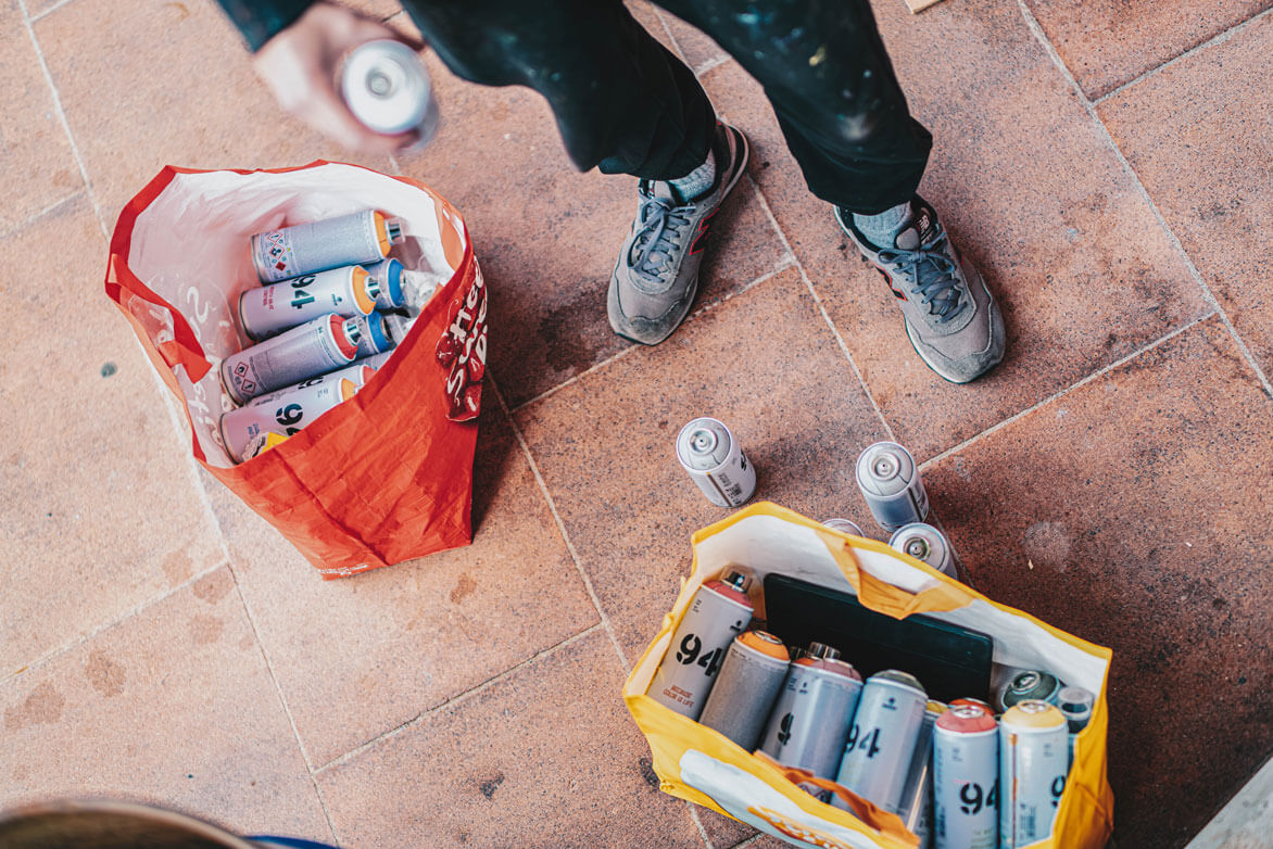 Person with two bags of spray paint cans