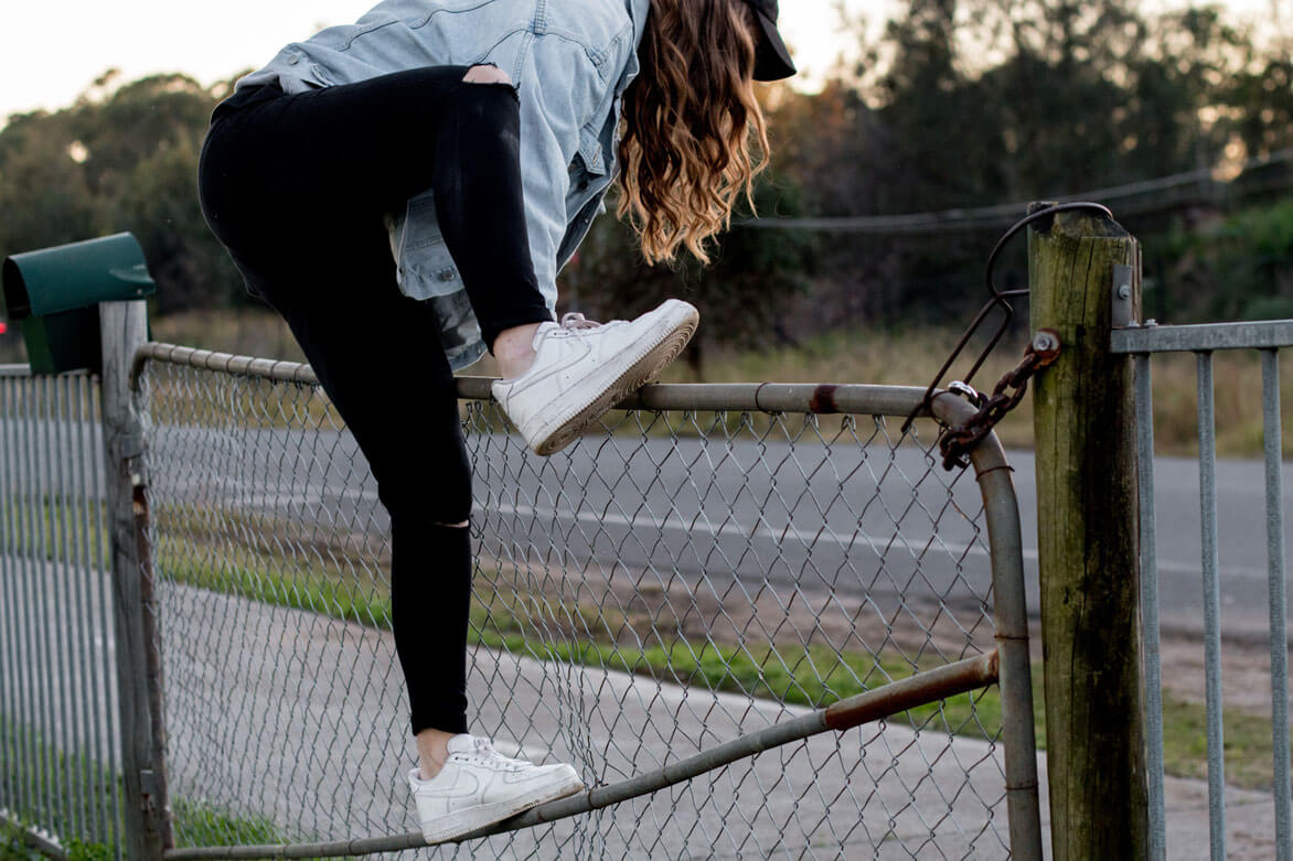 Young woman climbing over fence